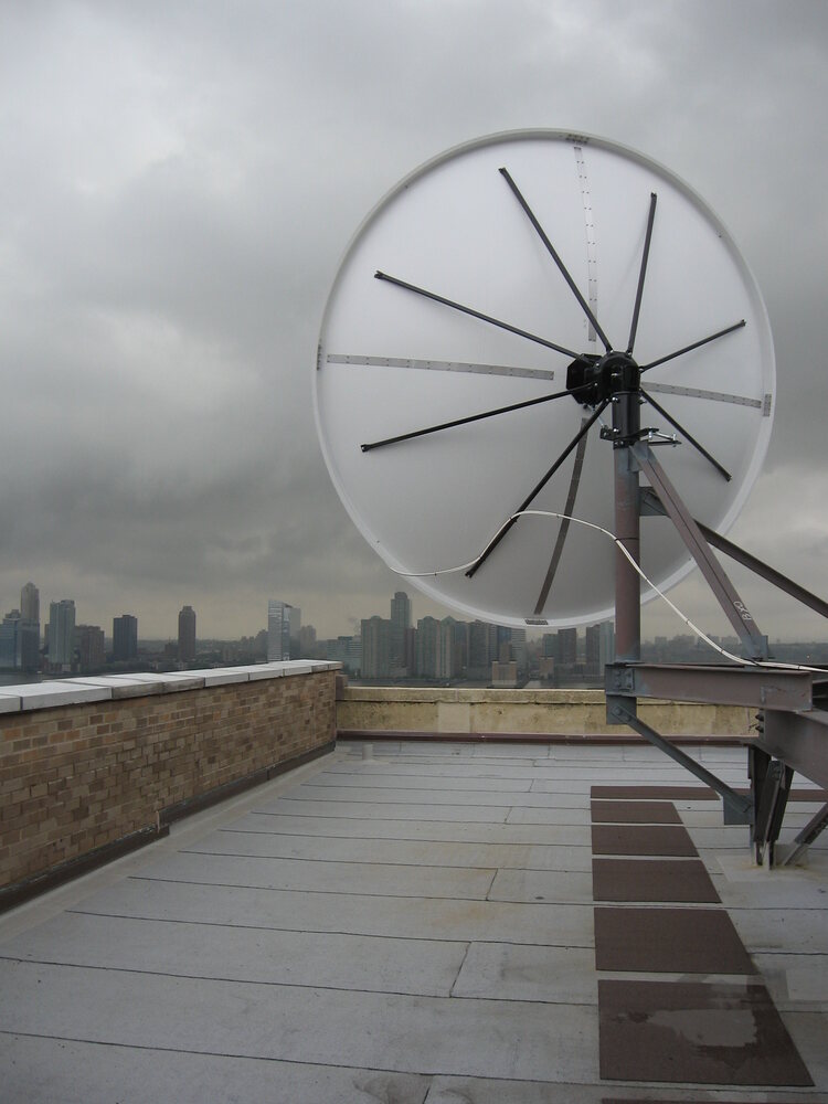 Specialty rooftop antenna against a city skyline